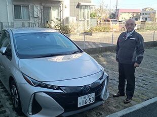 車の隣に立つ担当者の写真